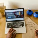 Workspace with laptop, packaging, and handwritten LLC notes, ideal for a small business startup scene.